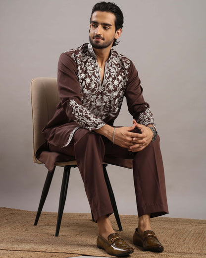 Model sitting in chair wearing Men’s Burgundy Royale Floral Embroidered Kurta by Crease India