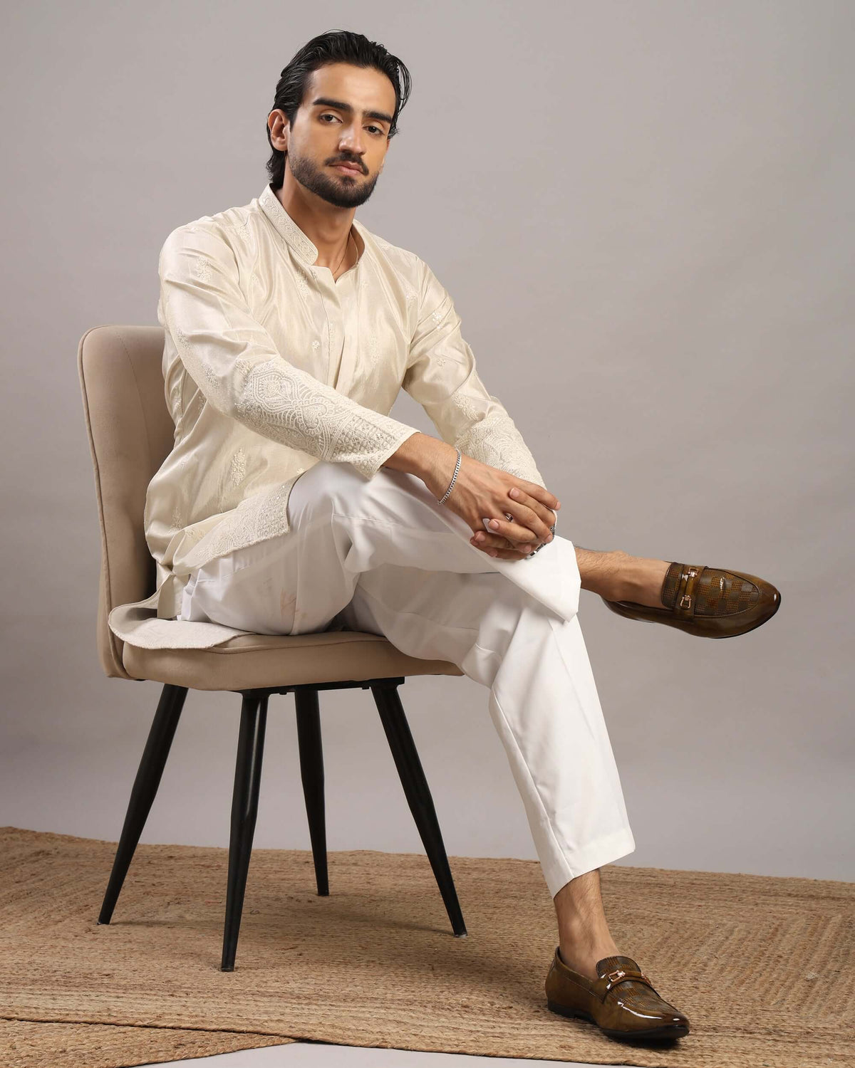 Model sitting in chair posing front in Men’s Cream Royale Floral Embroidered Kurta by Crease India