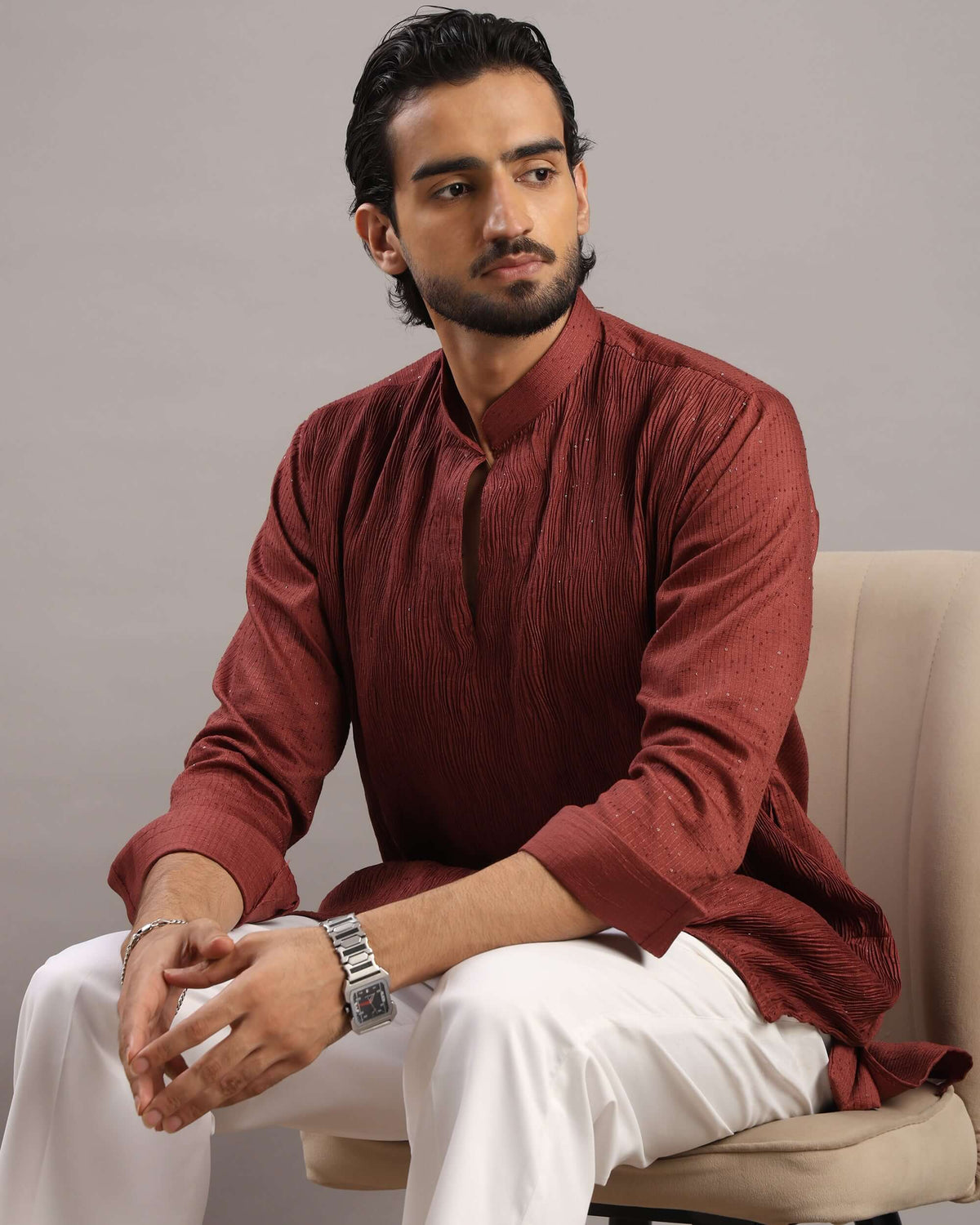 Model sitting in chair wearing Men’s Rust Red V-Neck Pleated Party Wear Kurta by Crease India